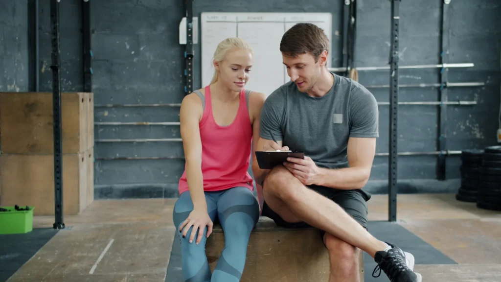Personal trainer reviewing a workout plan with a client in a gym