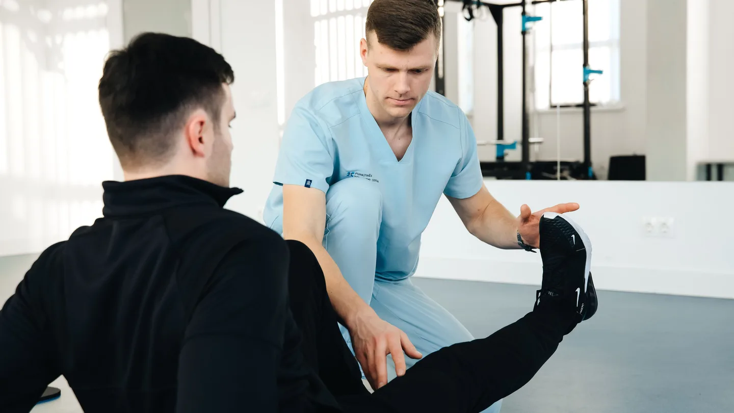 Physical therapist guiding a patient through a leg exercise during rehab