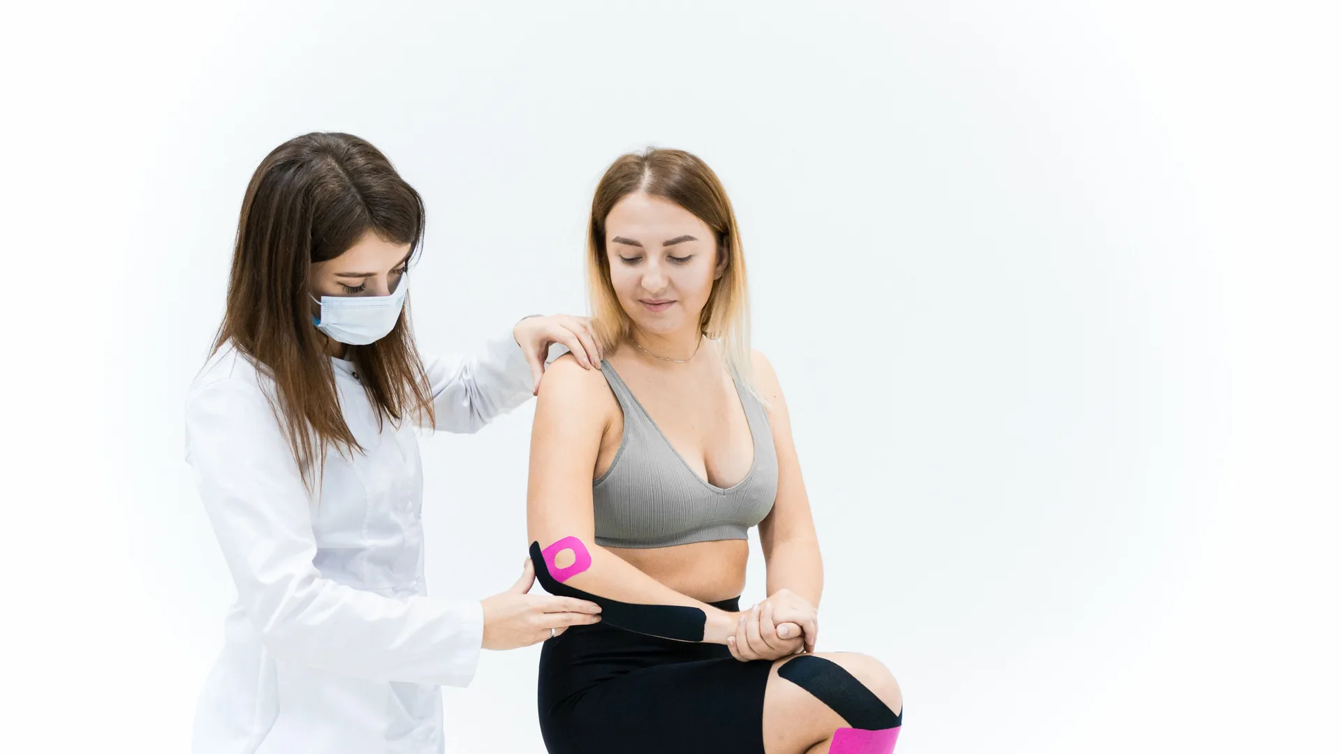 Therapist applying tape to a knee during a rehab session